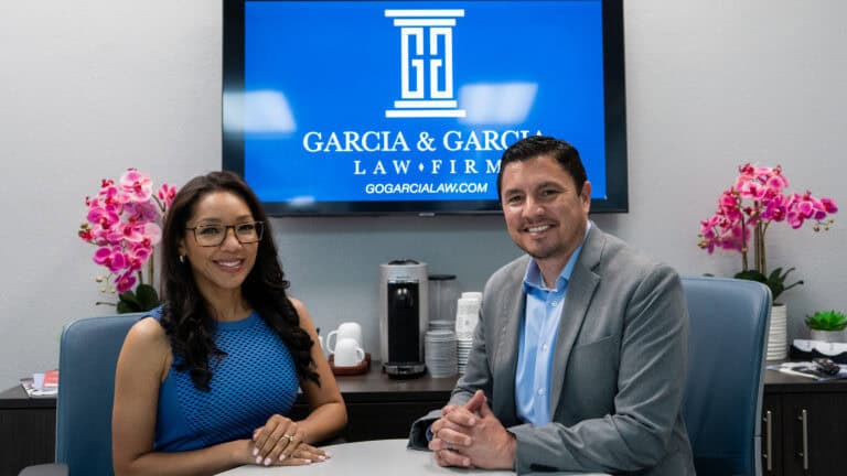 Attorneys at Garcia and Garcia Law Firm seated in an office, featuring a logo backdrop, promoting legal services and client representation.